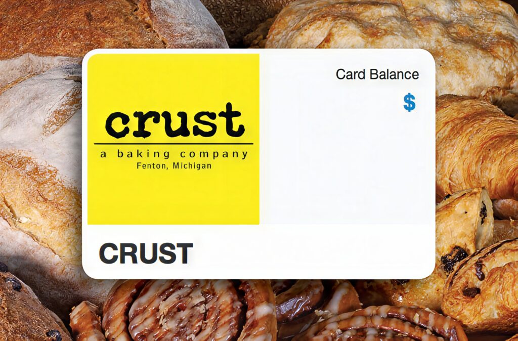 A CRUST eGift card showing its card balance, on a spread of fresh bread and pastries