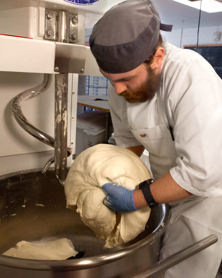 A CRUST bread baker lifting a large batch of dough out of the mixer